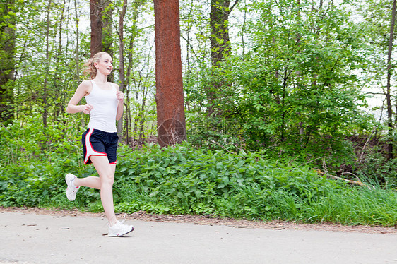 年轻女子在森林里慢跑活动公园赛跑者女士运动森林训练女性活力慢跑者图片