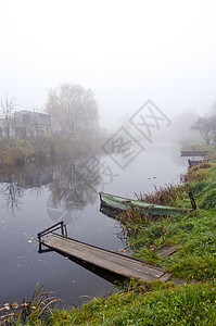 雾中沉没的河上木林船和桥图片