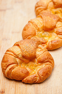 木板上新鲜烘烤的法国牛角面包脆皮美食金子面团新月包子小吃黄油面包早餐图片