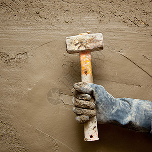 带手套的铁锤人 在石水泥背景下拼装砖墙石膏手工维修砂浆工具建造石工建筑学图片