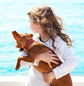 带着狗在海上的黑褐色女孩航行假期游艇娱乐家庭童年蓝色甲板黑发幸福图片