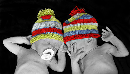 新出生的双胞胎 戴多彩色条纹帽子图片