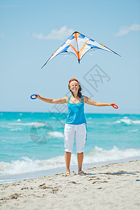 海滩上的女人玩着多彩的风筝活动喜悦童年青年享受孩子闲暇蓝色天空幸福图片