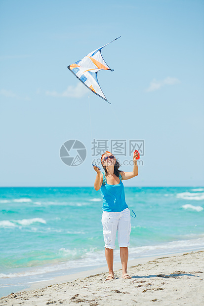 海滩上的女人玩着多彩的风筝空气快乐孩子热带童年喜悦天空幸福晴天情感图片