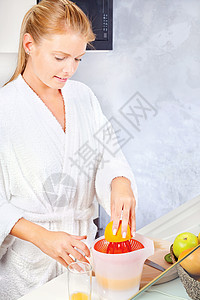 女人在厨房做早间果汁水果奇异果早餐金发橙子微笑女性食物长袍图片