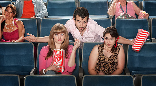 男人在戏剧中调戏女朋友观众看台爆米花青少年零食娱乐夫妻倾斜剧院图片