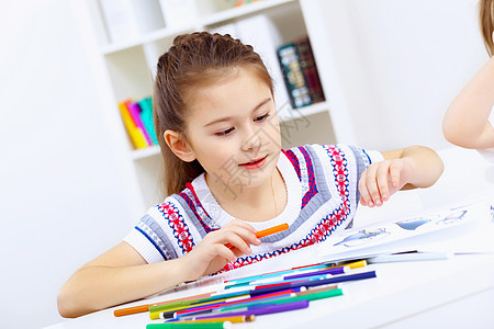 女孩和学习青年微笑笔记本家庭作业婴儿桌子铅笔工作女学生幼儿园图片
