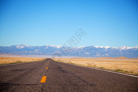 空高速公路驶近山地山脉沙漠自由蓝色天空场景孤独沥青车道城市地平线图片