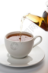 向孤立的白杯中倒茶波纹茶壶芳香早餐水滴草本植物补品咖啡店杯子饮料图片