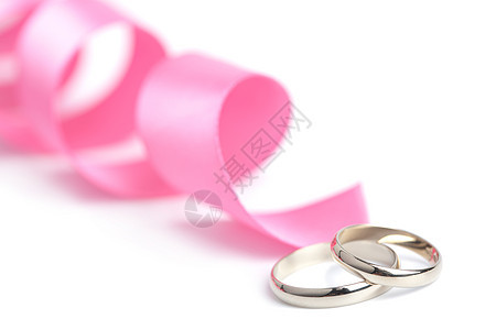 金结婚戒指和粉色丝带被孤立图片
