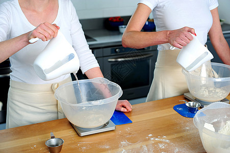 女性用手把水倒进面粉碗图片
