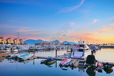 金海岸日落的游艇 在香港海岸线场景奢华蓝色城市港口酒店桅杆海岸天空图片