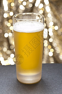 在色彩多彩的背景面前的杯子黄色玻璃高脚杯泡沫餐厅橙子强光酒馆啤酒杯啤酒图片