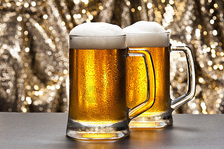 在闪闪发光的背景面前的啤酒杯派对闪光玻璃庆典泡沫啤酒啤酒厂豪饮气泡静物图片