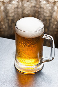 在闪闪发光的背景面前的啤酒杯金子派对背光庆典玻璃饮料液体闪光啤酒烧杯图片