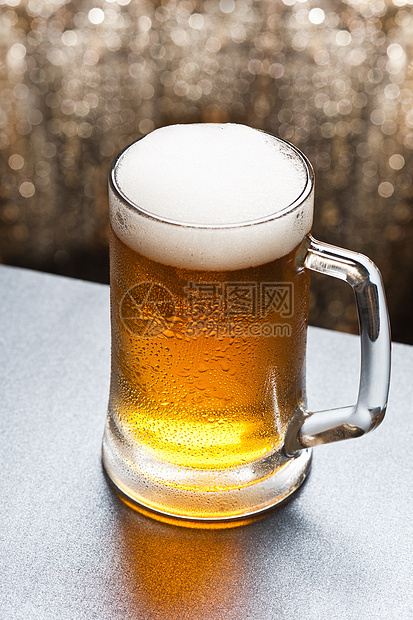 在闪闪发光的背景面前的啤酒杯金子派对背光庆典玻璃饮料液体闪光啤酒烧杯图片