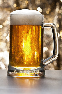 在闪闪发光的背景面前的啤酒杯背光烧杯泡沫玻璃静物饮料派对草稿金子啤酒厂图片