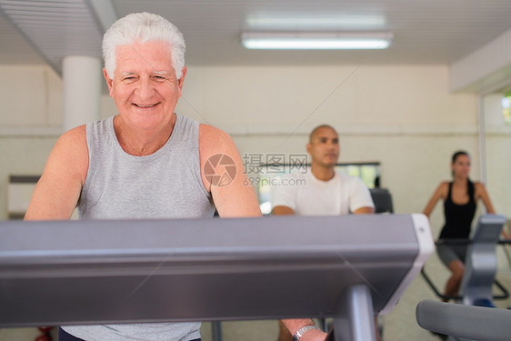 高级男子在健康俱乐部锻炼微笑运动装跑步机成人健身退休男性老年人出汗跑步图片