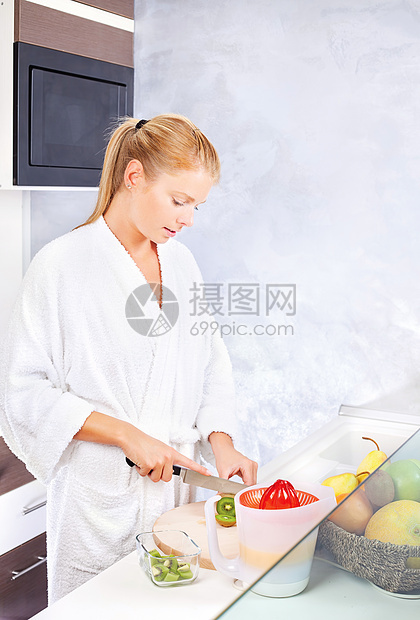 妇女在厨房做水果沙拉女性金发长袍微笑橙子食物果汁奇异果早餐图片