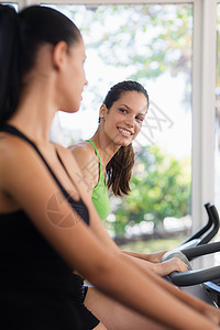 体操中健身自行车训练的年轻漂亮女孩活动运动闲暇微笑朋友们友谊女性乐趣女孩们健身房图片