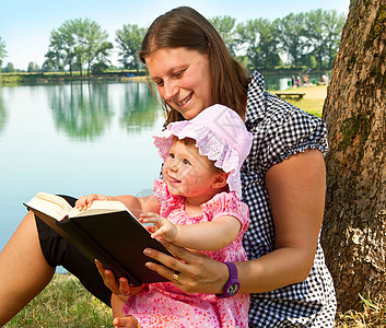 与母亲一起读书的小女孩公园草地孩子女性乐趣幸福家庭女儿闲暇童年图片