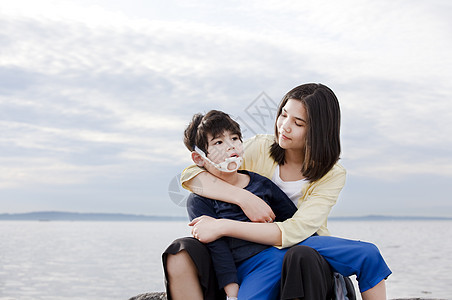 年幼妹妹在沙滩上抱着残疾兄弟图片