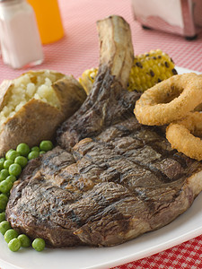 Ribeye牛排与Baked马铃薯豆洋葱环和Ribeye牛排在骨头上烹饪盐瓶烧烤炉生产牛肉蔬菜肋眼厨艺食物晚餐图片