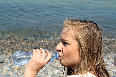 十几岁的女孩饮用水微笑口渴黑发青年蓝色享受女性青少年女士瓶子图片
