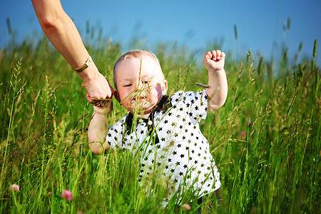 男孩和母亲的手蓝色孩子儿子闲暇童年天空草地微笑生活婴儿图片