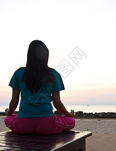 日落时在海滩冥想的女人活力女孩头脑衣服漂浮沉思海洋瑜伽反射身体图片