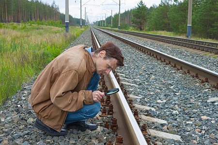 人坐在铁路上 手握放大镜图片