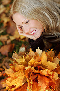 秋叶中的妇女脚尖季节成人女士乐趣微笑女性公园毛衣眼睛橙子图片