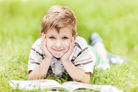 爱读书的孩子在户外阅读书本的男孩子儿子男生童年家庭孩子男性草地太阳公园享受背景