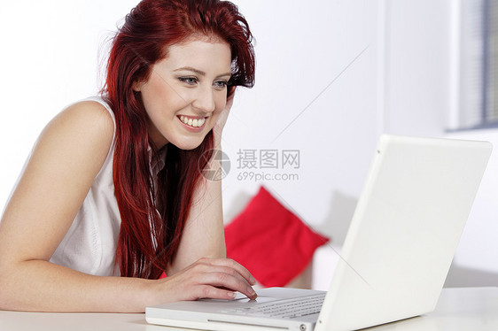 妇女在家里使用膝上型电脑微笑头发女性女士快乐红色笔记本图片