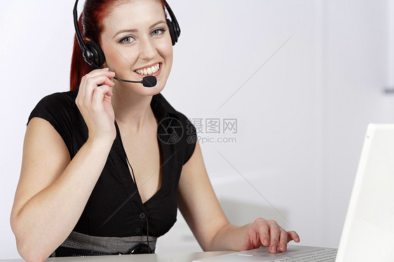 女人在电话里说话耳机女性女士工作微笑笔记本电脑讲话办公室快乐图片