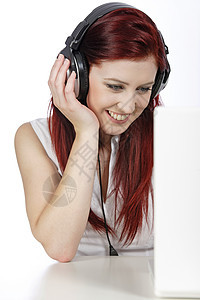 使用笔记本电脑手持耳机的妇女女士红色音乐微笑快乐女性头发图片