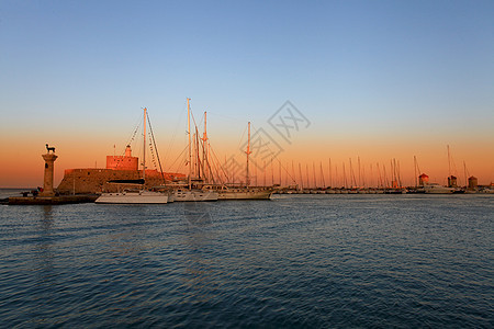 日落时 希腊的罗得港和风车码头雕像纪念碑天空地标海洋玫瑰旅游日出海景图片