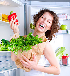 美丽的年轻女子 在冰箱附近 有健康食物的冷冻机饮食杂货店厨房营养重量早餐身体蔬菜沙拉损失图片