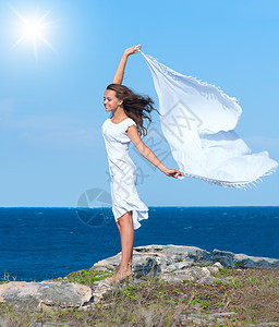 自由概念 有白刀疤的女孩站在岩石上裙子旅行海岸海洋翅膀乐趣蓝色海滩假期热带图片
