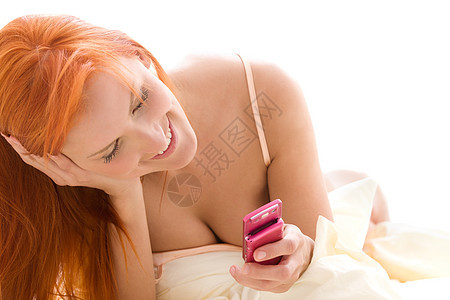 带手机的快乐红发女人微笑互联网女孩电子邮件阅读电话网络上网冲浪细胞图片