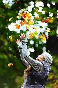 秋天公园的女子落叶微笑女孩享受女性叶子乐趣家庭投掷幸福青年图片