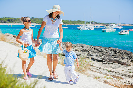 三口三口家庭在热带海滩上行走幸福母亲喜悦男生情调游艇海滨孩子太阳镜女性图片