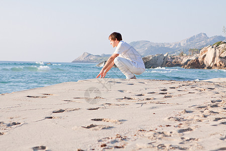 青年男子在暑假的沙滩上放松快乐男人海洋微笑假期成人天空旅行蓝色旅游图片