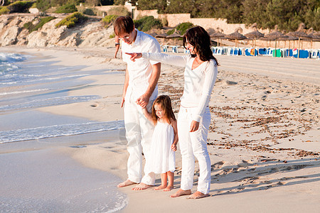 快乐的年轻家庭 和女儿在沙滩上蓝色成人男人海滩母亲旅行父母喜悦团体旅游图片