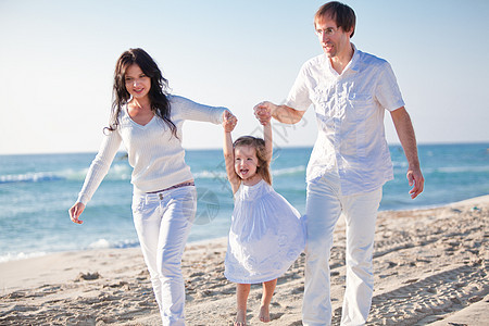 快乐的年轻家庭 和女儿在沙滩上幸福孩子女性男人海滩成人父母团体男性蓝色图片