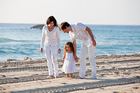 爸爸孩子快乐的年轻家庭 和女儿在沙滩上孩子海滩母亲男性父母喜悦女士蓝色团体父亲背景