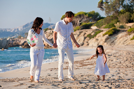 快乐的年轻家庭 和女儿在沙滩上假期女孩团体女性乐趣旅行蓝色父亲旅游海滩图片