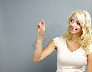 快乐的年轻女人指着成人灰色微笑手指幸福女性金发交际金发女郎图片
