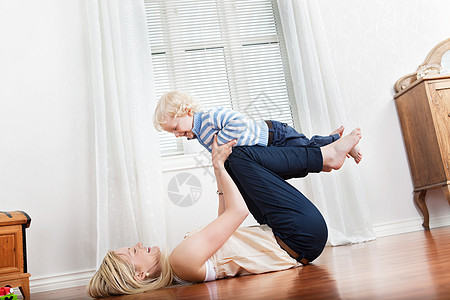 母亲与婴儿男孩玩耍童年母性赤脚快乐飞机金发父母纽带喜悦孩子图片
