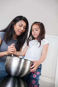 母亲和女儿在厨房烘烤桌子女士团结女孩烹饪教学女性孕产家庭童年图片